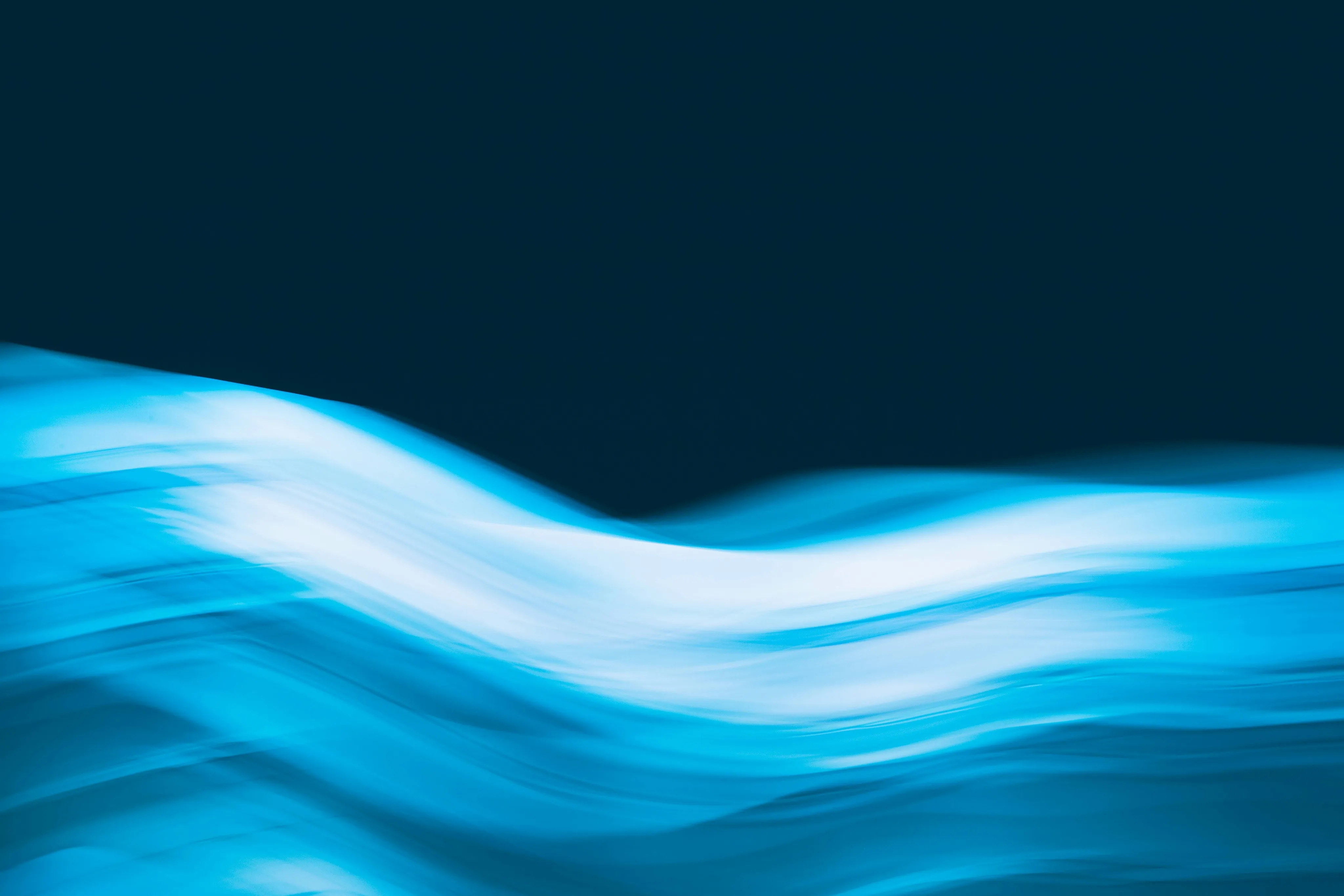 Abstract blue light waves flowing across a dark navy background